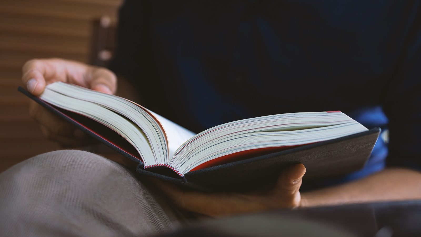 young man is sitting reading in the window in the room with soft Foto: memorystockphoto/AdobeStock